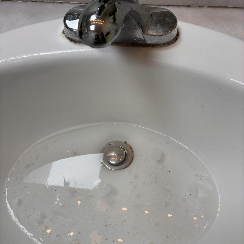 Bathroom basin sink drain partially clogged with water