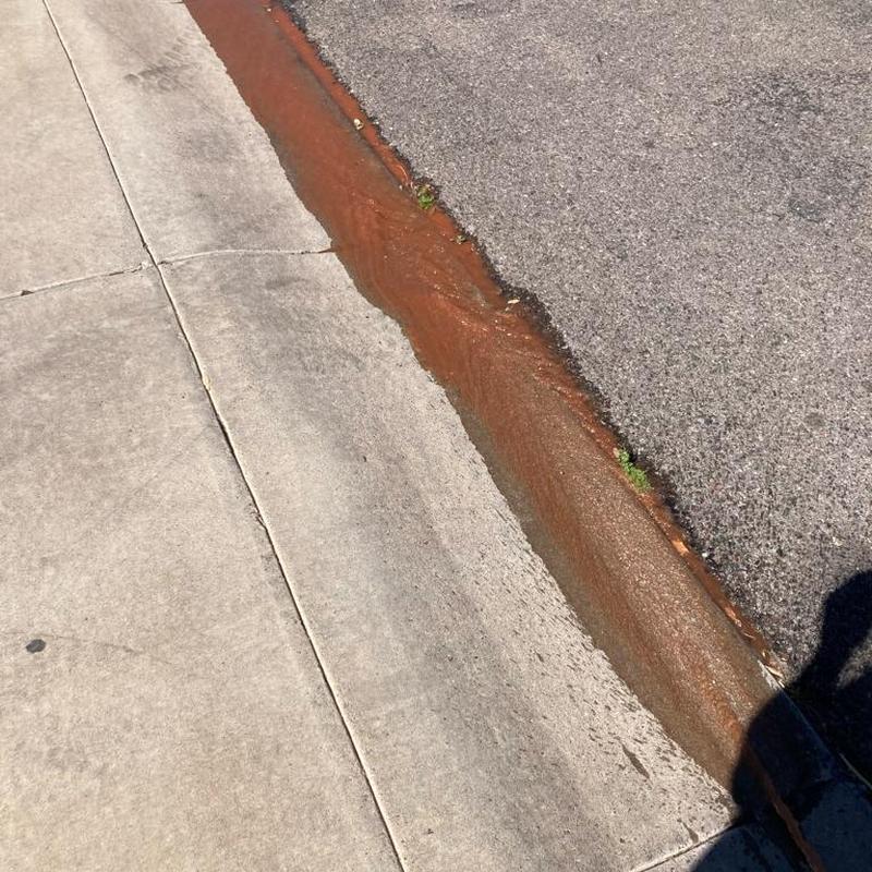 Rusty water heater sediment draining on street curb Rusty water heater sediment draining on street curb