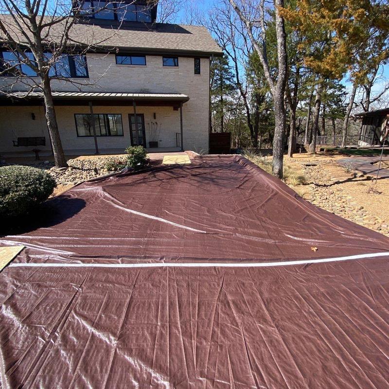 Driveway protective tarp over stained concrete surface