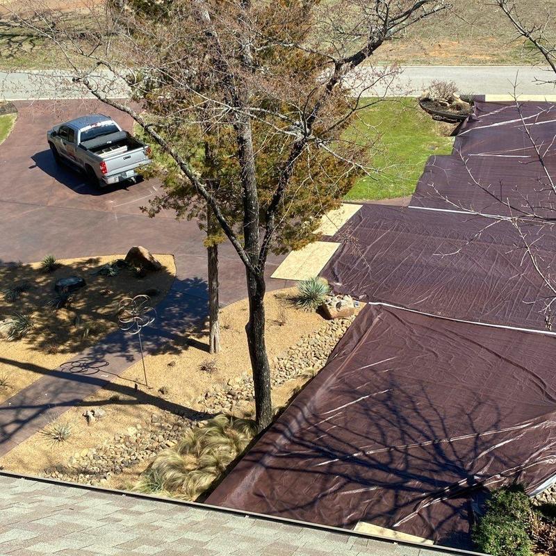 Stained driveway protected with tarp during roofing job