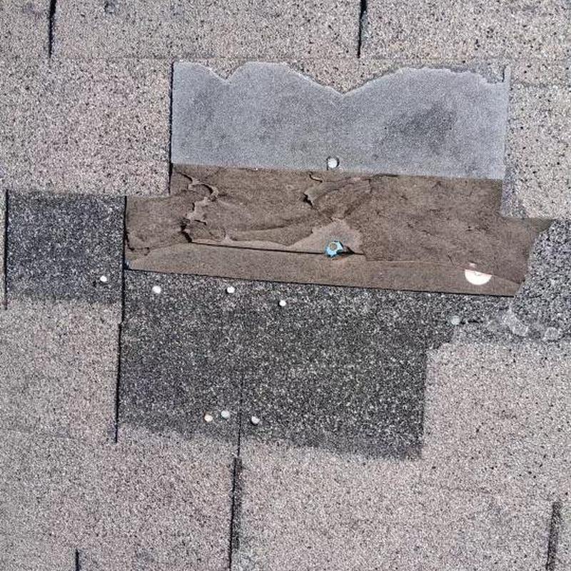 Damaged roof shingles with exposed underlayment and nails