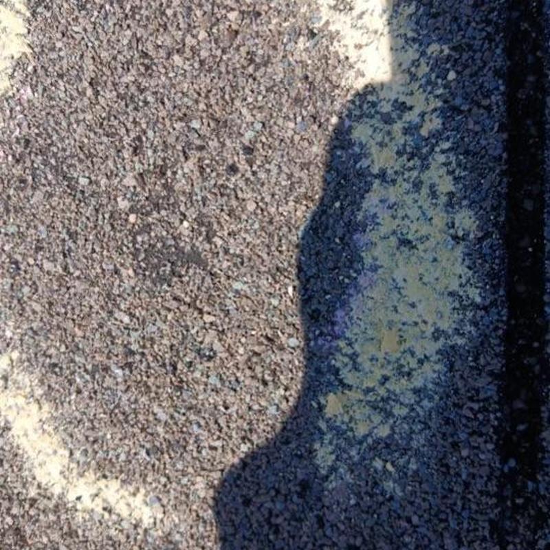 Asphalt shingle granule loss on roof surface above shadow