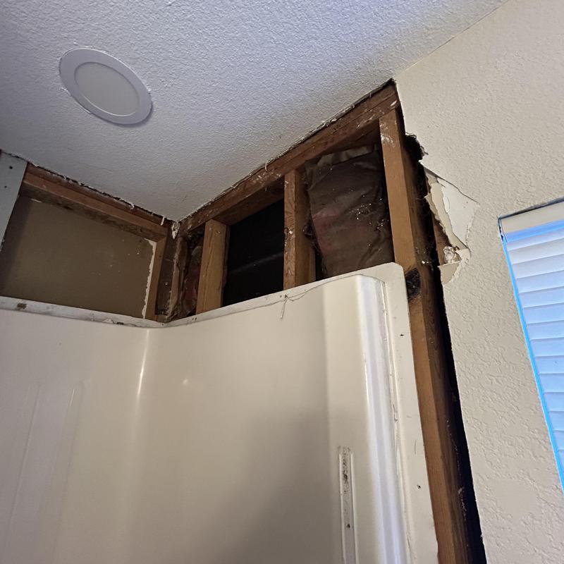 Shower wall with exposed studs and damaged sheetrock