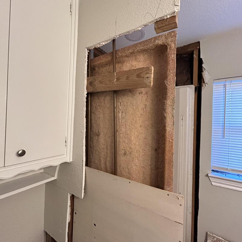 Restroom drywall removal showing water damage and insulation
