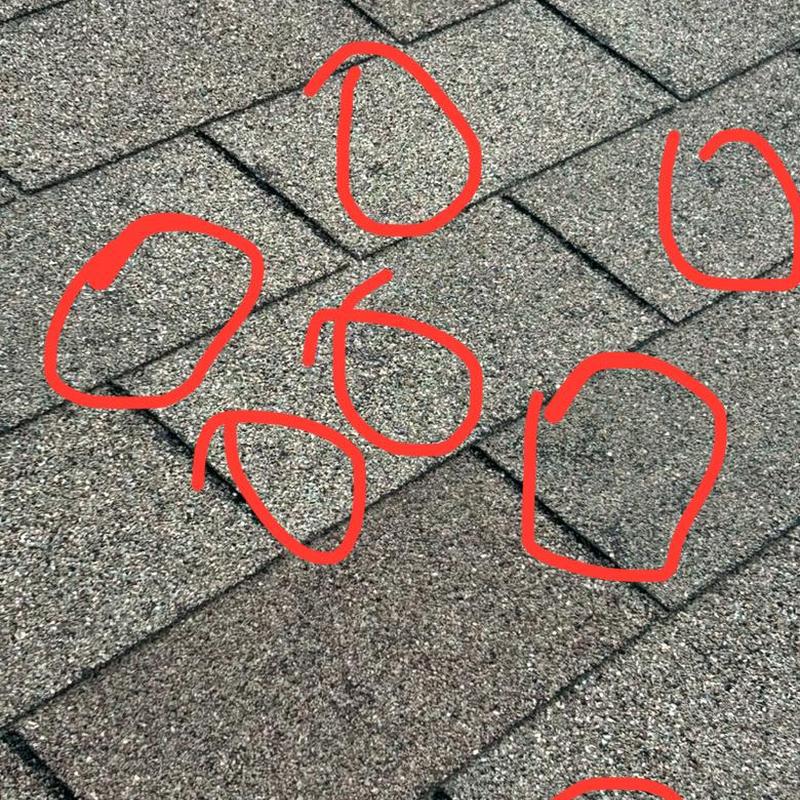 Roof shingles with hail impact damage marked in red
