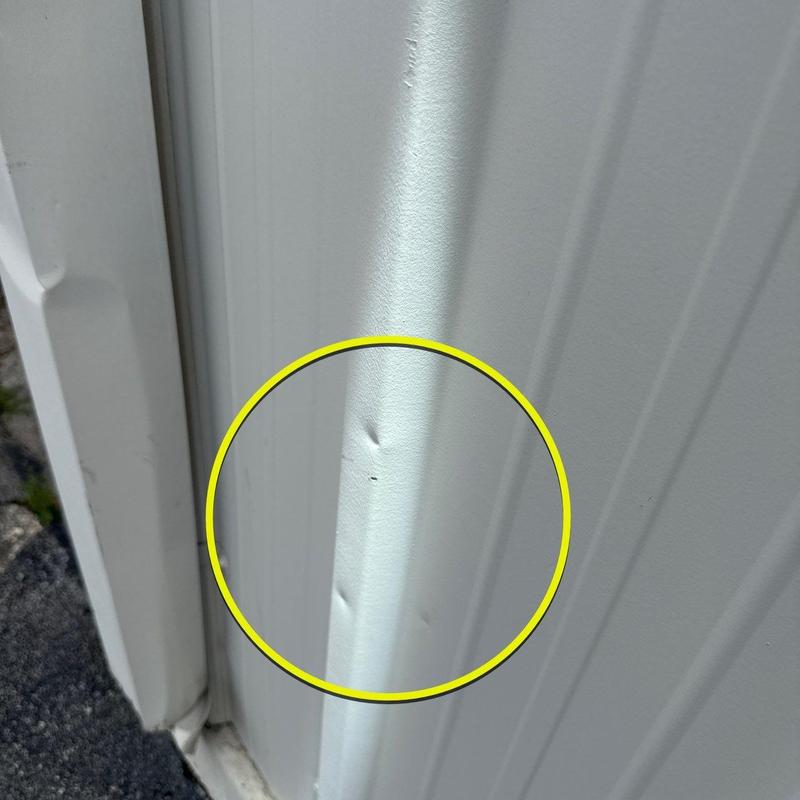 Metal roof panel with hail damage dents highlighted