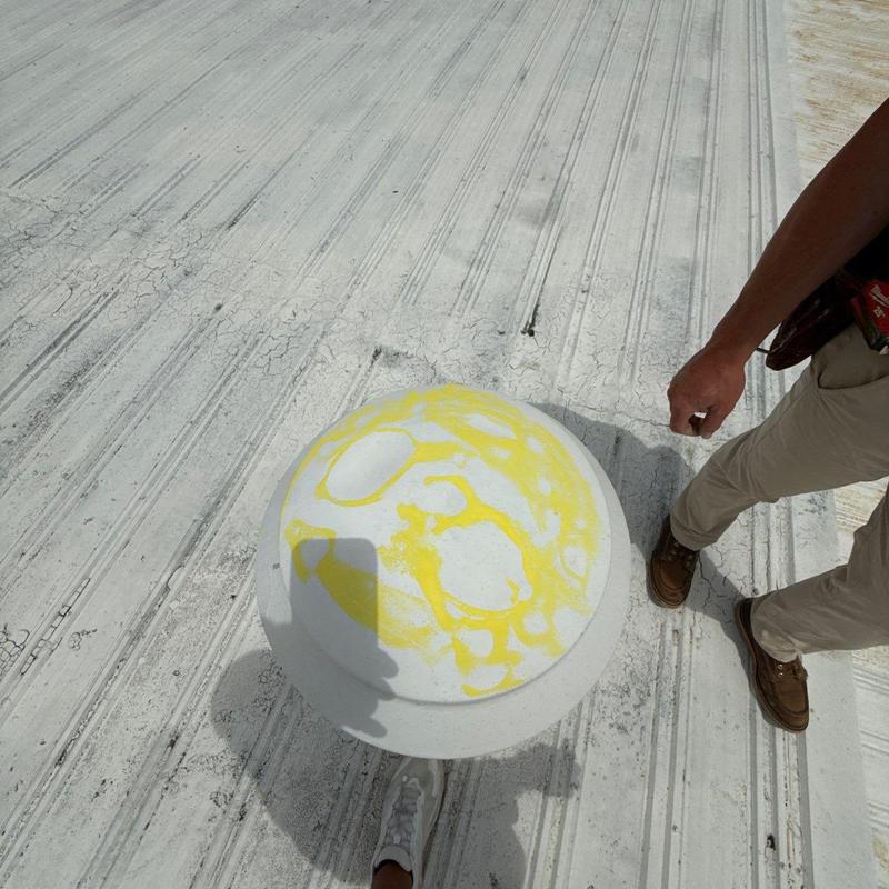 Roof vent with yellow sealant on metal roofing panel