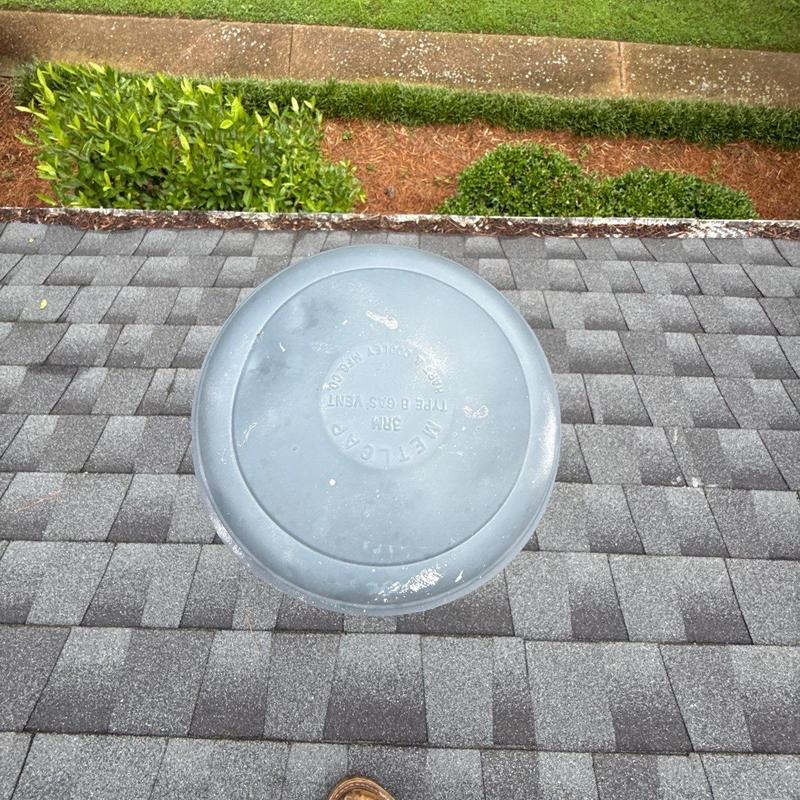 Roof vent on shingled roof with garden background