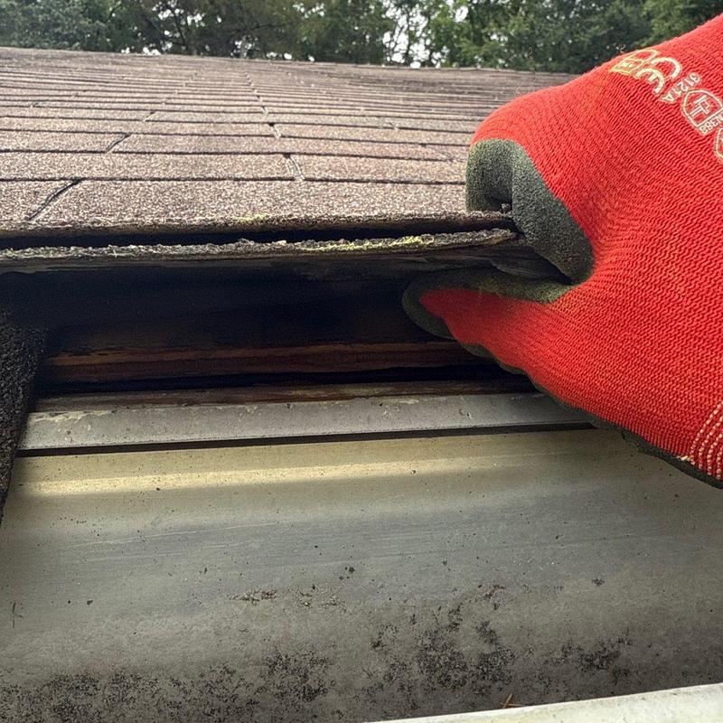 Roof shingles wind lifting inspection near gutter edge