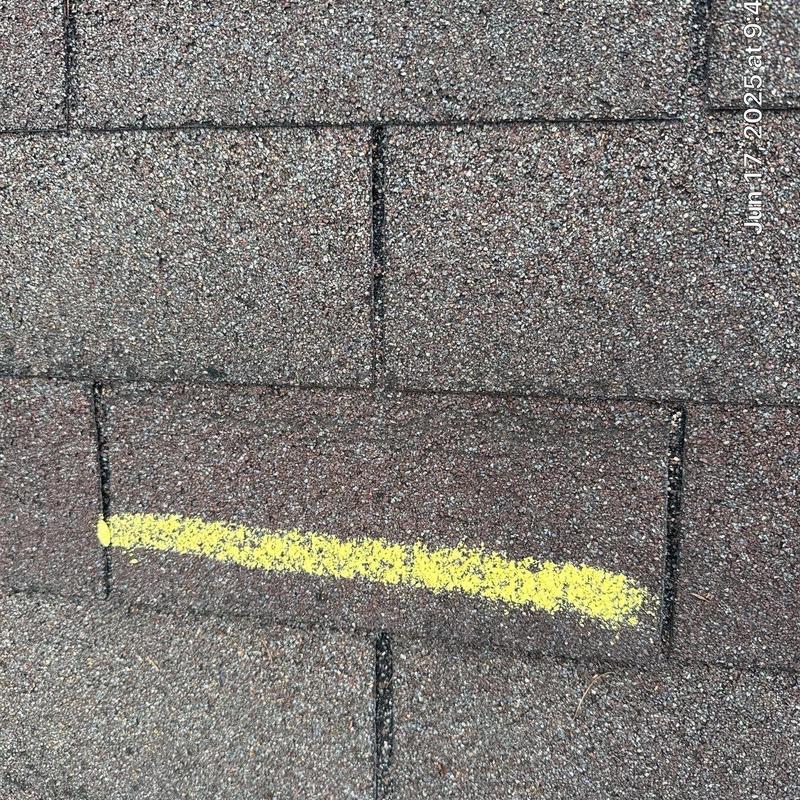 Roof shingles with yellow chalk marking on storm damage