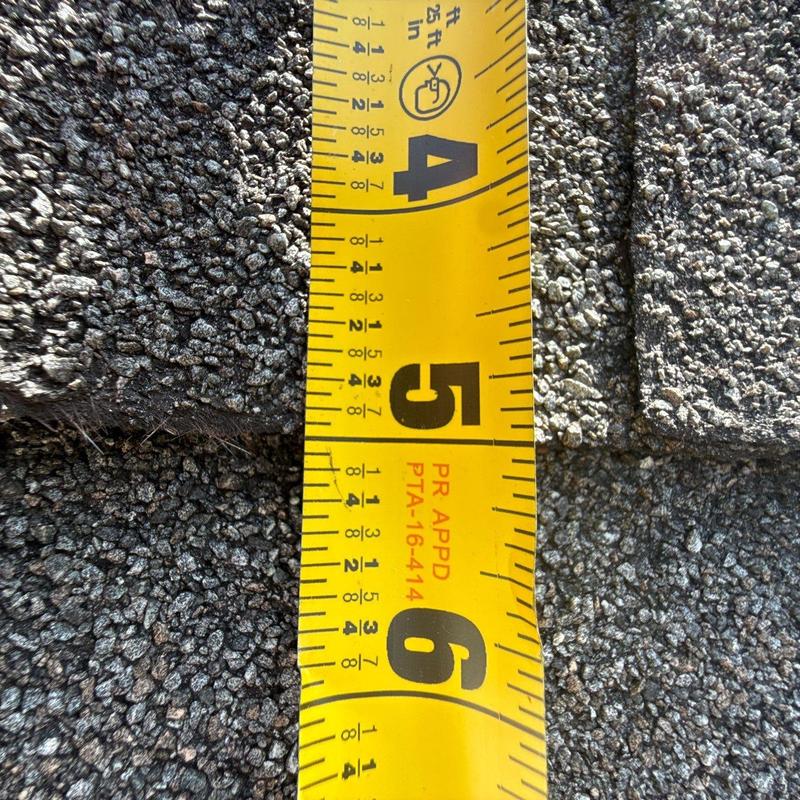 Asphalt shingle roof close-up with measuring tape
