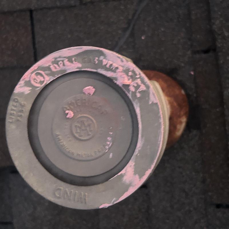 Roof ventilation cap with weathered paint on shingle roof