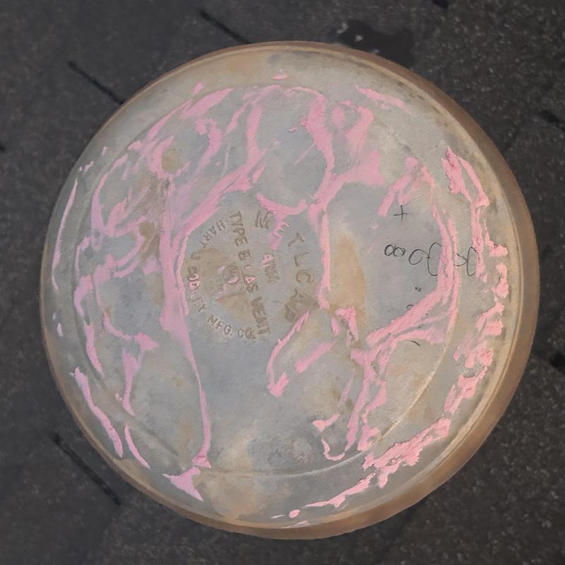 Roof vent cap with pink sealant applied on metal surface