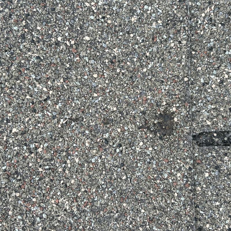 Asphalt shingle roof granules close-up with damage spot