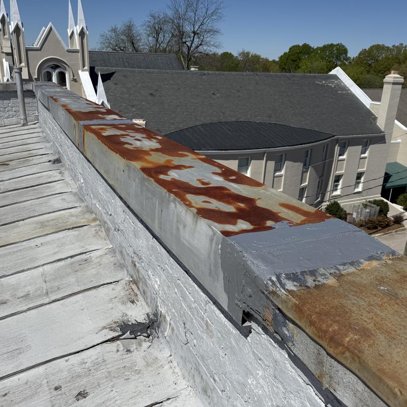 Metal coping with rust spots on historic roof edge