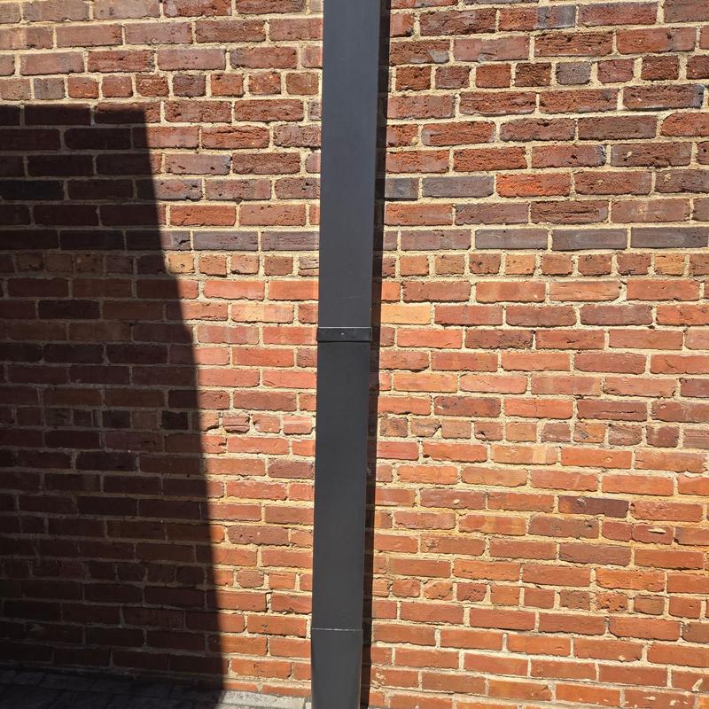 Commercial downspout on brick building exterior wall Commercial downspout on brick building exterior wall
