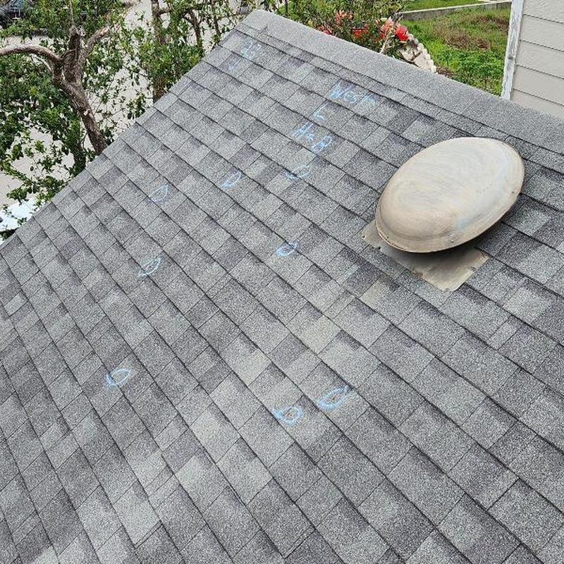 Asphalt roof shingles with hail damage marked in chalk Asphalt roof shingles with hail damage marked in chalk