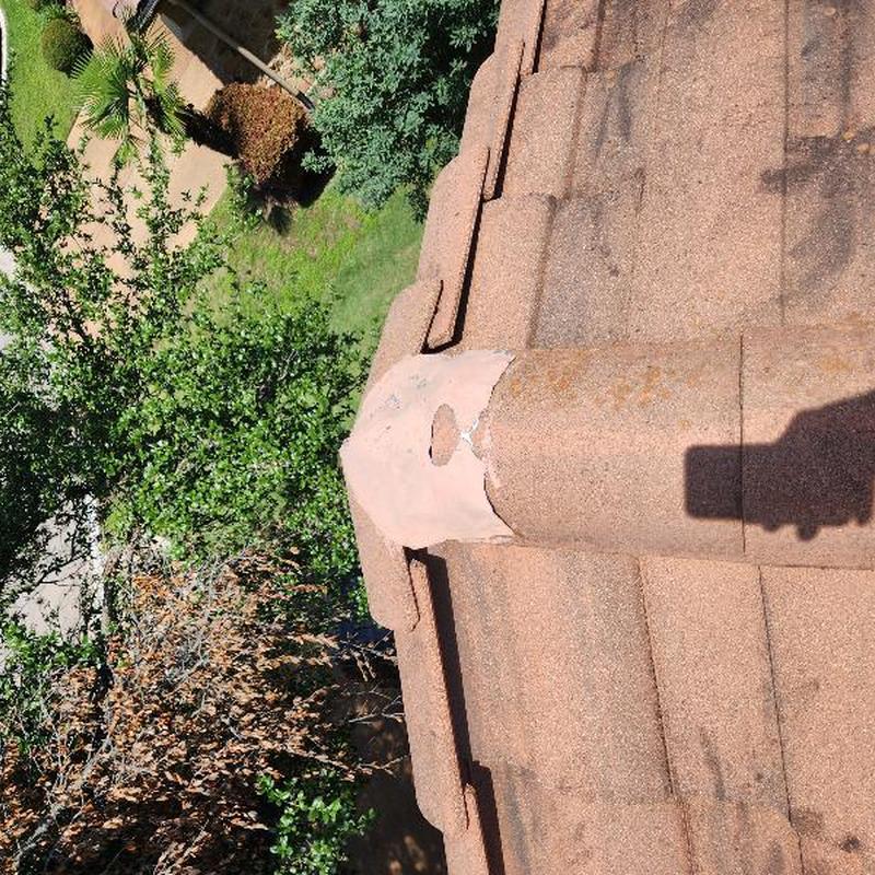 Clay tile roof with damaged ridge cap tile and hole Clay tile roof with damaged ridge cap tile and hole