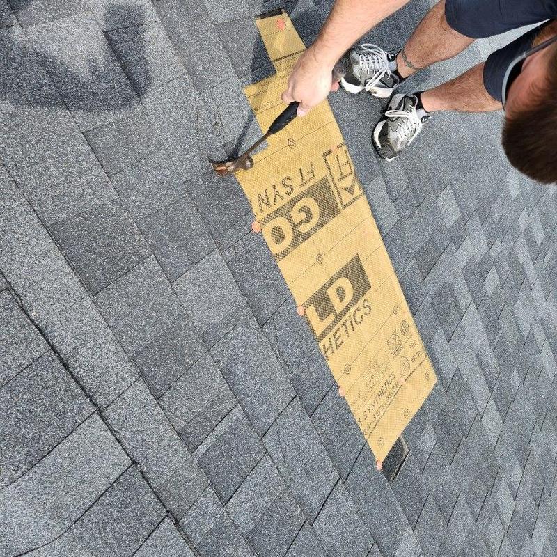 Charcoal black roof shingles installation with hammer Charcoal black roof shingles installation with hammer