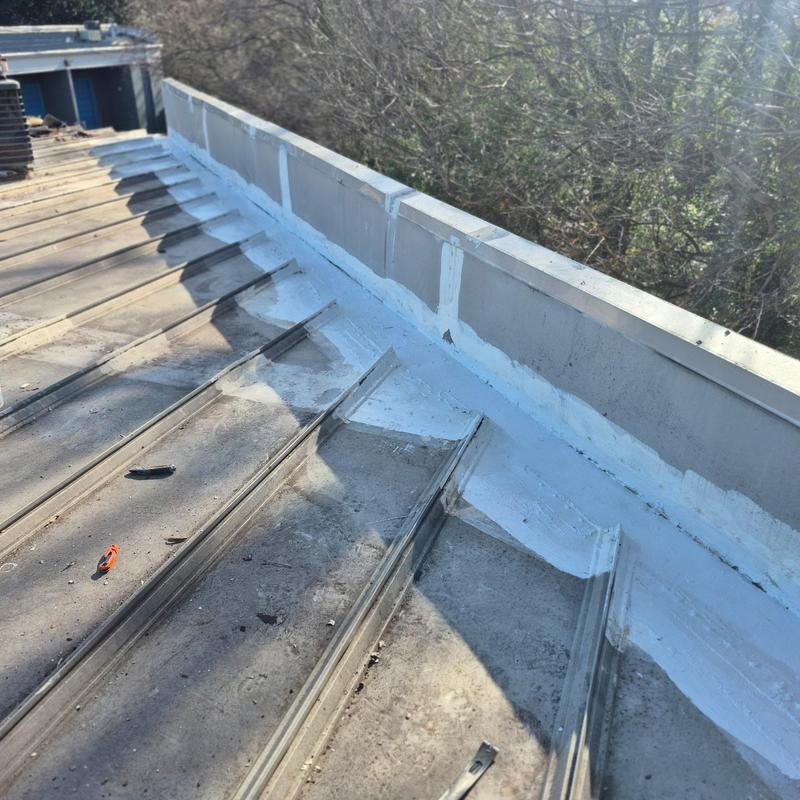 Metal roof wall tie-in with fluid-applied coating