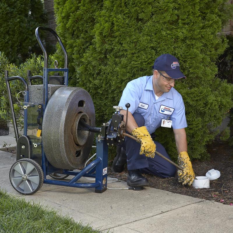 Drain cleaning machine with plumber clearing clog outdoors