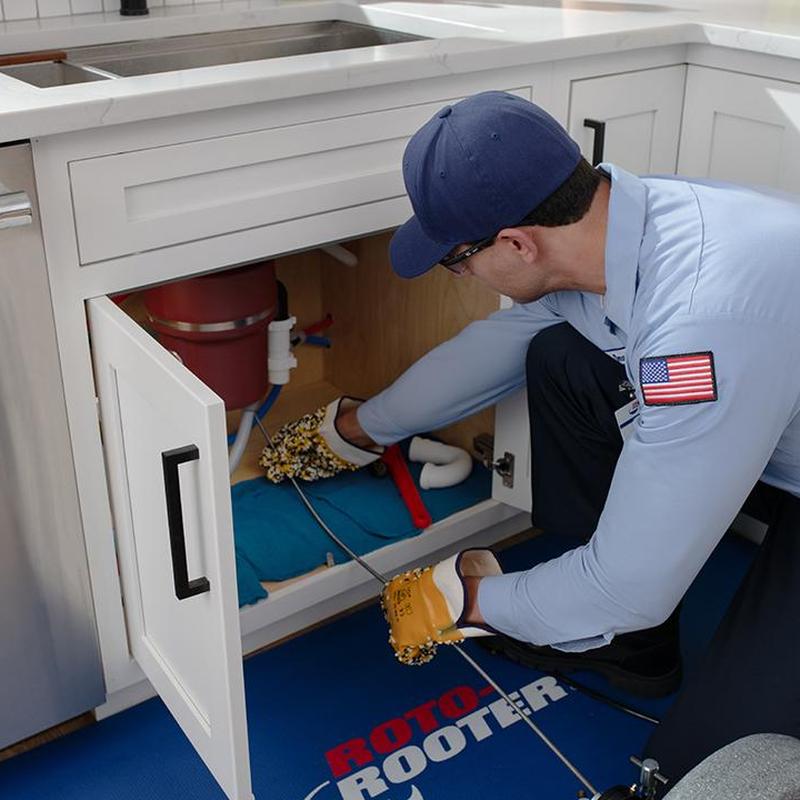 Kitchen sink drain clog with plumber using auger tool