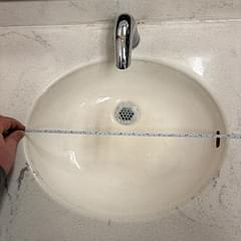 Bathroom sink basin with measuring tape across width