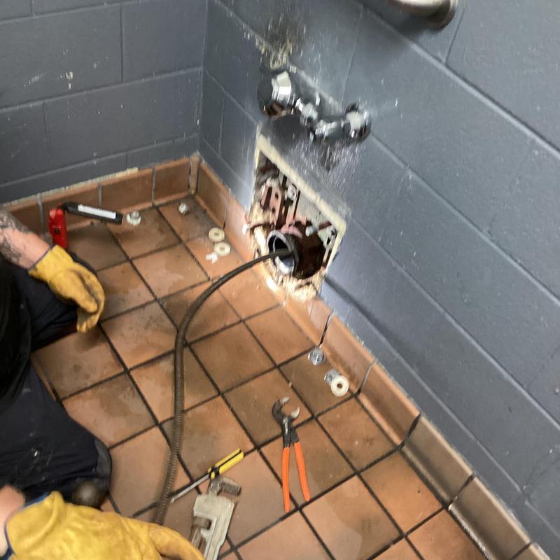 Service main line clog with drain snake in bathroom wall