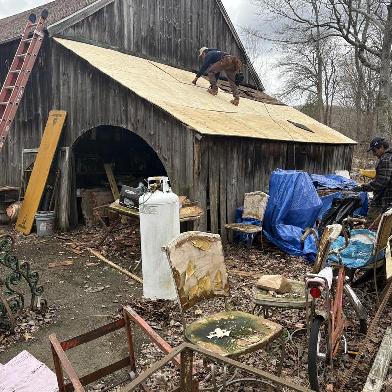 Plywood roof installation on barn with workers