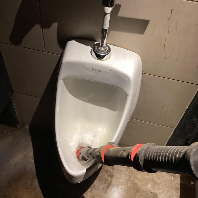 Urinal drain clearing with plumbing auger tool