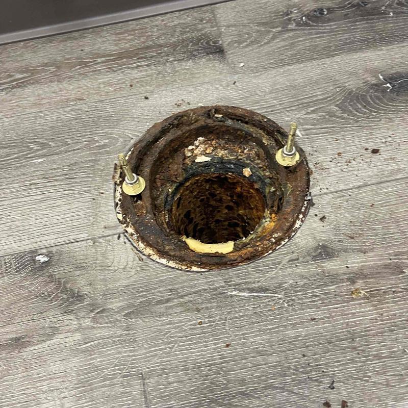 Toilet flange with rust and drywall floor damage Toilet flange with rust and drywall floor damage