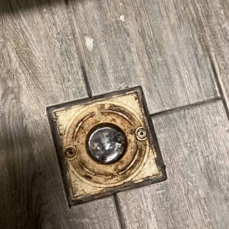 Floor drain cover on tiled lab floor with rust