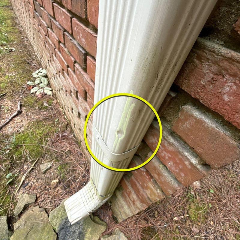 Downspout dent and damage on brick wall exterior
