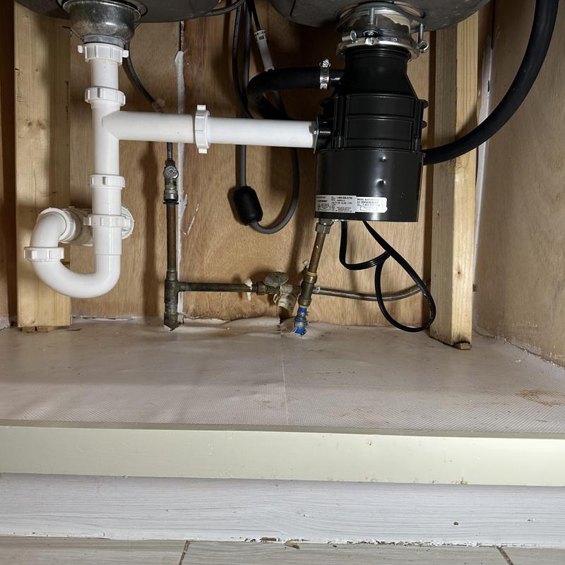 Garbage disposal installation with drain piping under sink