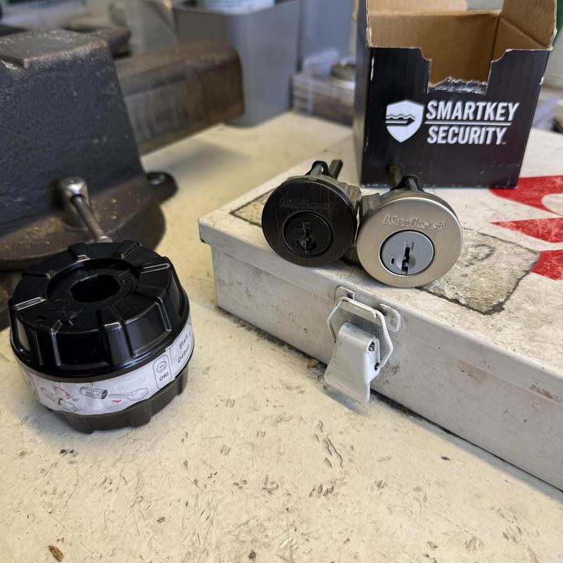 Kwikset lock cylinders with SmartKey packaging on bench