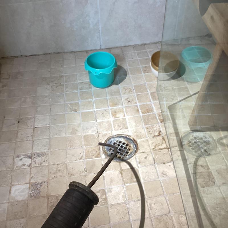 Shower drain cleaning with cable tool in tiled floor
