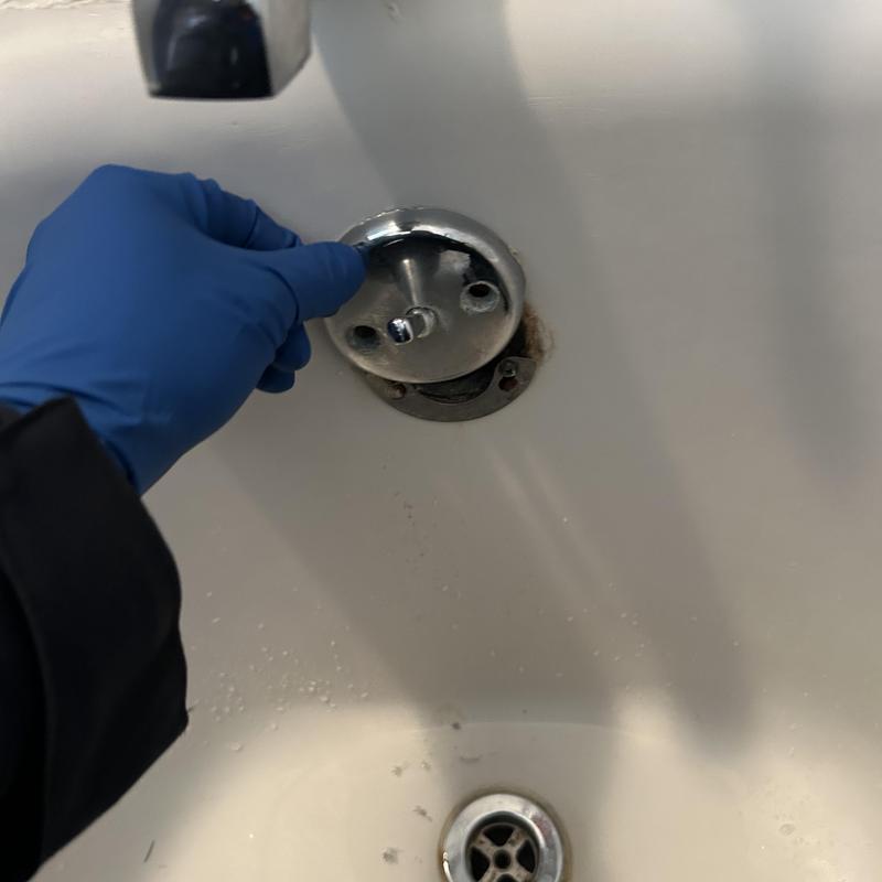 Bathtub drain stopper removal with gloved hand