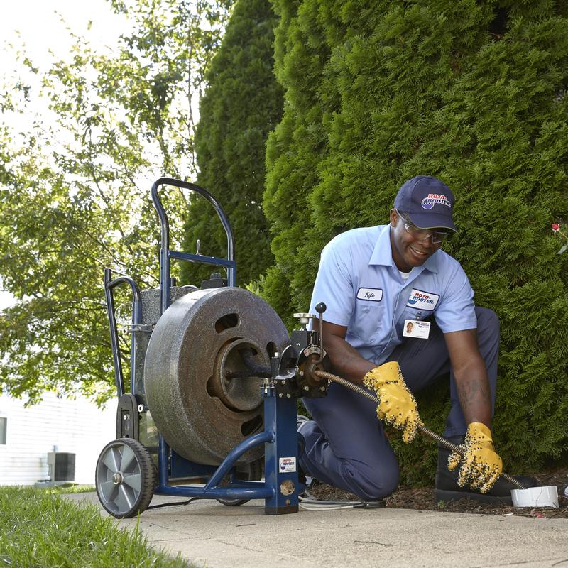 Drain cleaning machine with plumber clearing clog outdoors