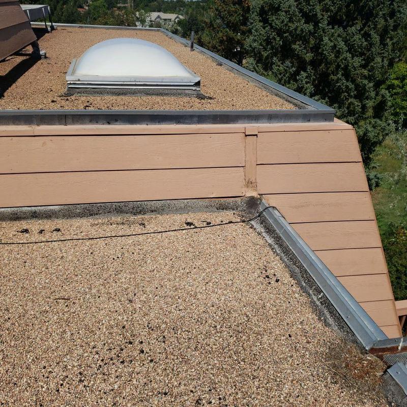 Tar and gravel flat roof with skylight and damaged edge