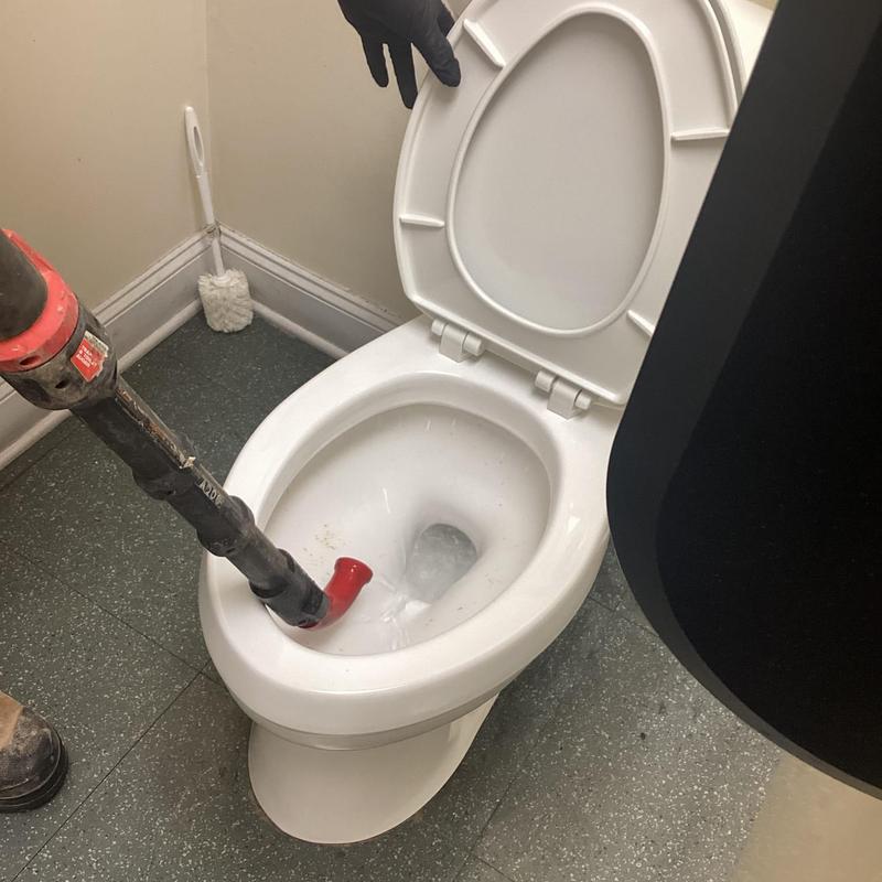 Toilet clog clearing with cable in restroom