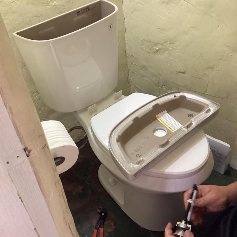 Toilet tank installation with bolt tightening in small bathroom
