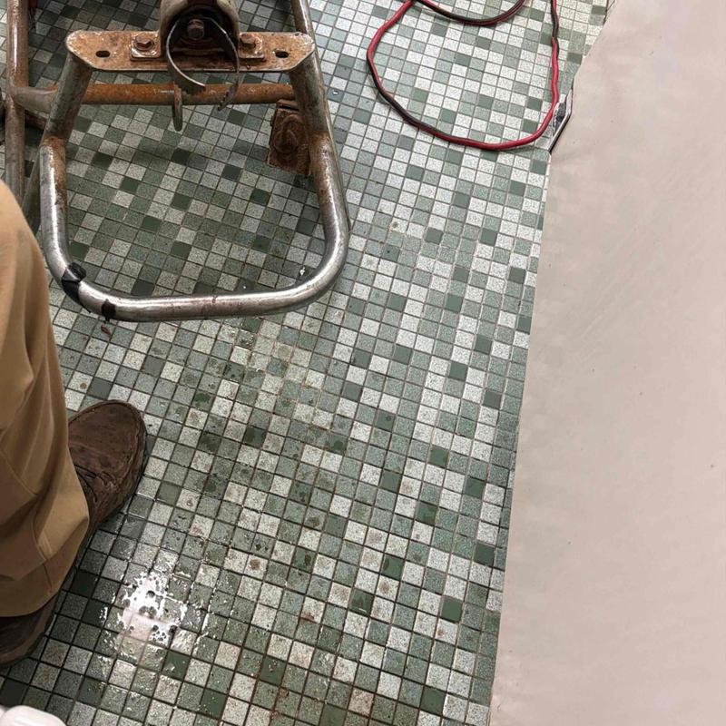 Toilet plumbing with cleaning tools on tiled floor