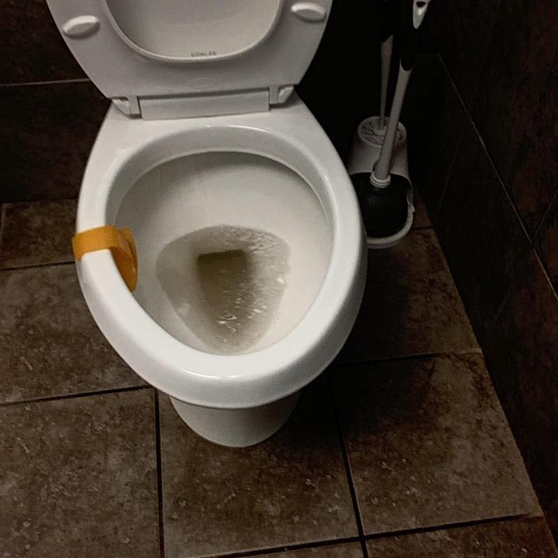 Commode with partial water blockage in warehouse restroom