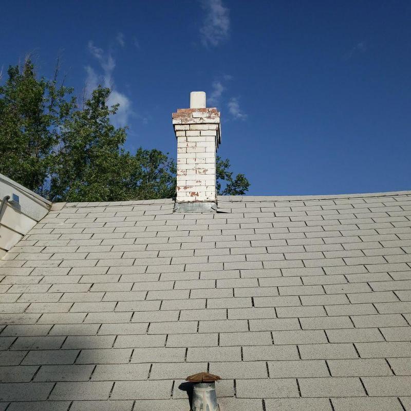 Chimney flashing on gray shingle roof under clear sky