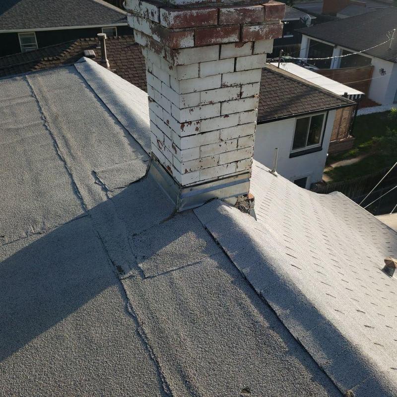 Chimney flashing on gravel roof with patchwork repairs