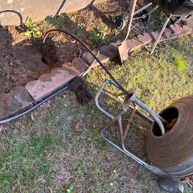 Bathtub drain cleaning with plumbing snake outside home