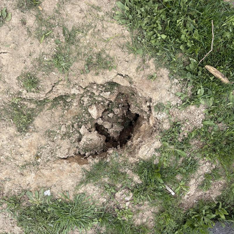 Water service line hole in yard with exposed dirt Water service line hole in yard with exposed dirt