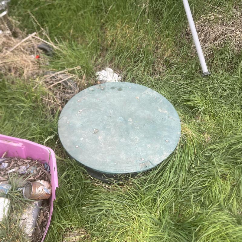 Septic tank pump-out with green lid in grass Septic tank pump-out with green lid in grass