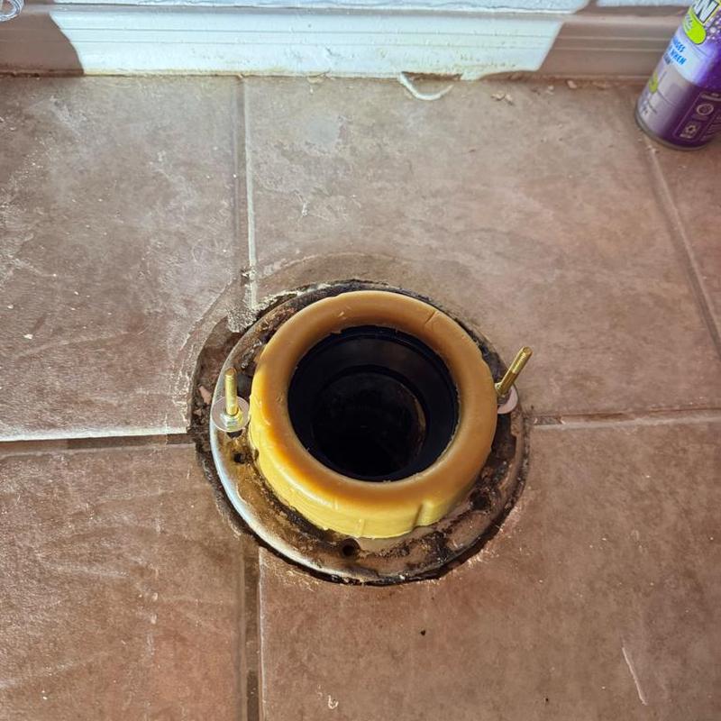 Toilet flange with new wax ring installed on tiled floor