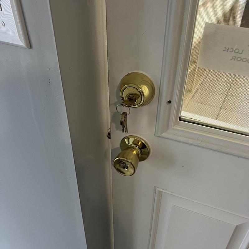 Door lock with keys and doorknob on white door
